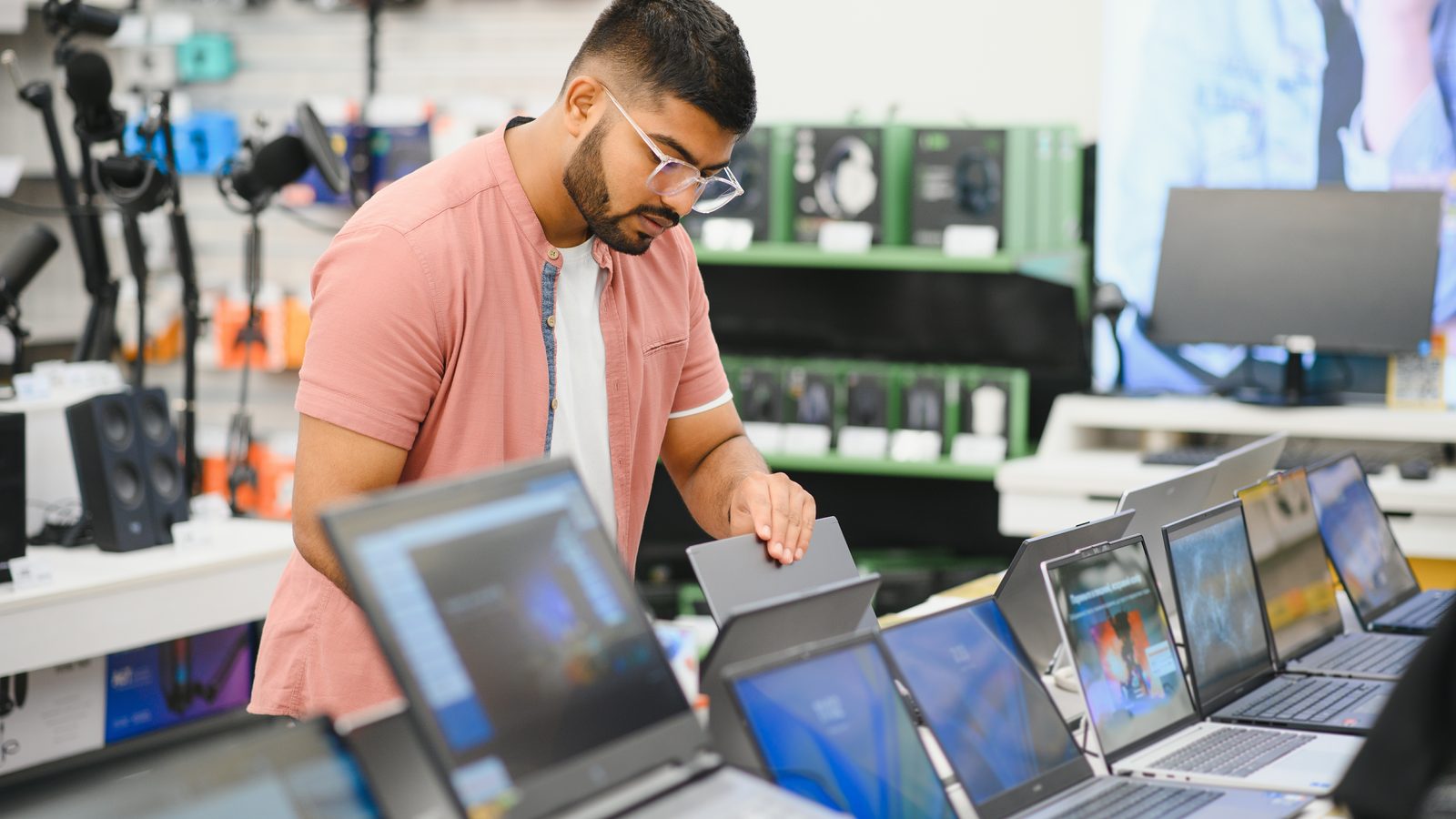 A male buyer looks at laptops in the computer department of the electronics store