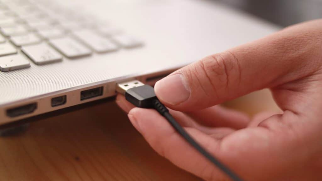 Close up of hand inserting plugging data cable into usb port in laptop data transfer concept