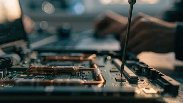 Close-up of a laptop motherboard with copper heat pipes during a repair