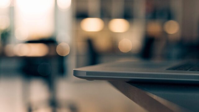 Close-up of the speaker grille edge of a matte grey laptop on an office desk