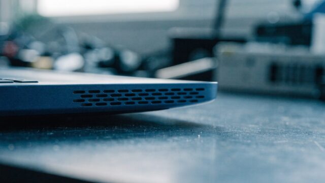 Close-up of the speaker grille edge of a dark blue laptop on a workbench