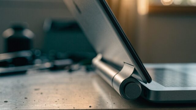 Close-up of the hinge and screen edge of a matte grey laptop on a workbench