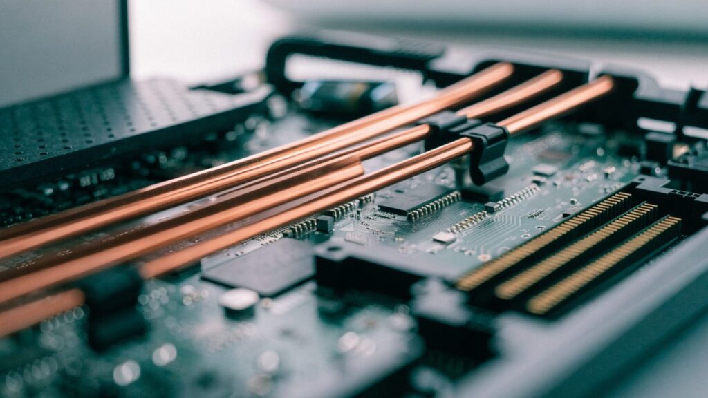 Close-up of a laptop motherboard with copper heat pipes during a repair
