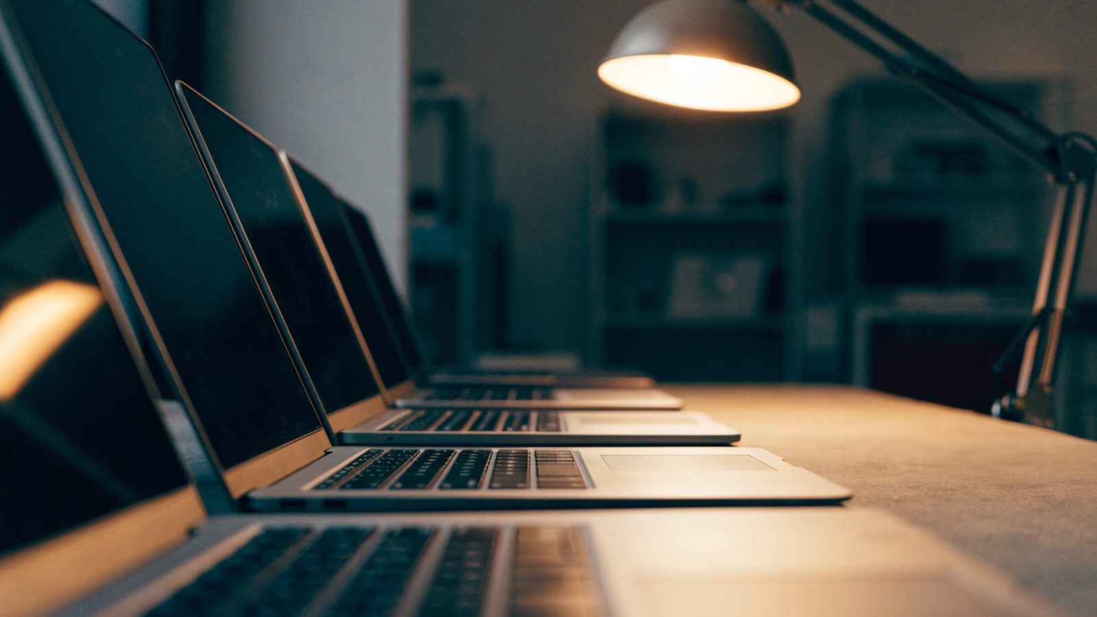 Several modern laptops lined up in a row on a workbench