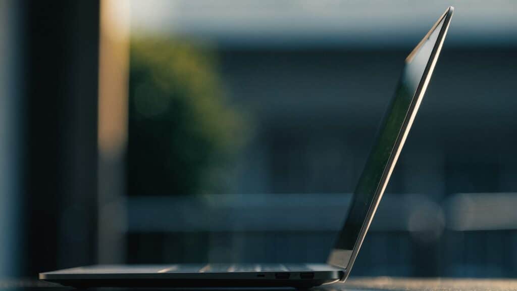 A slim matte grey laptop half open photographed from the side