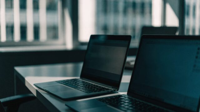 Two laptops side by side on an office desk as if being compared