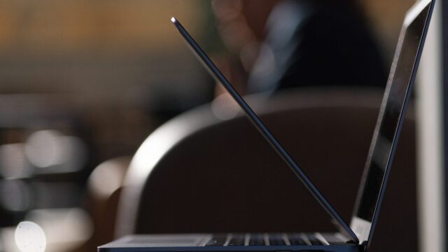 A slim dark blue laptop half open photographed from the side