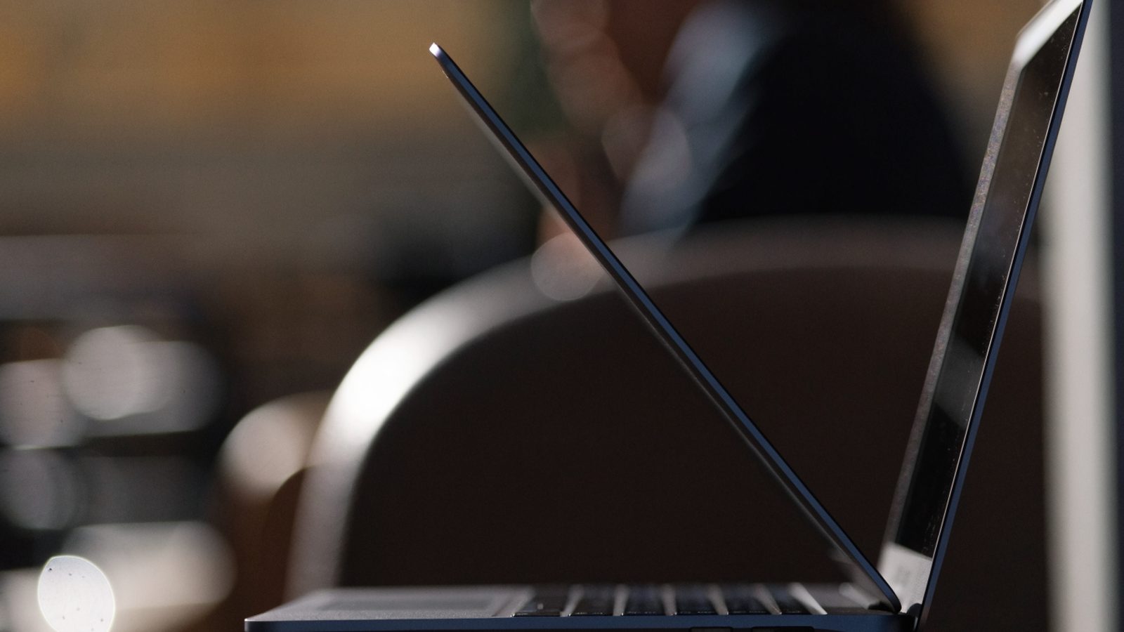 A slim dark blue laptop half open photographed from the side
