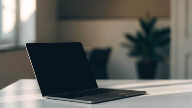 A matte grey laptop on a white desk with a completely dark blank screen