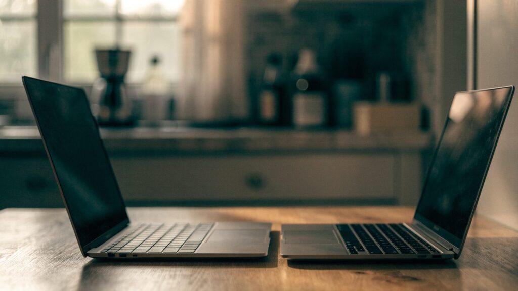 Two laptops side by side on a kitchen table as if being compared