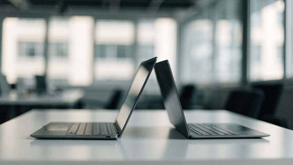 Two laptops side by side on a white desk as if being compared