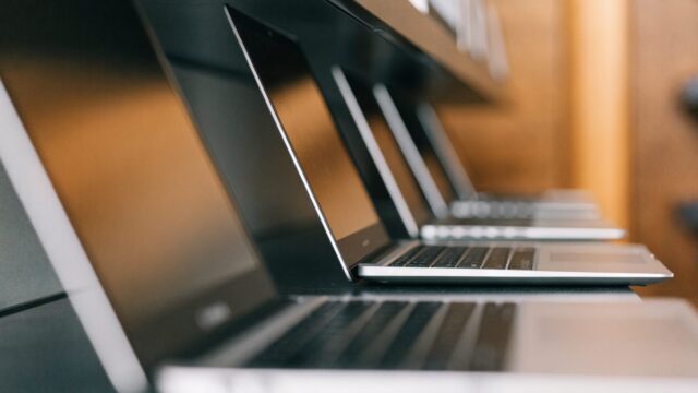 A row of new laptops on display on a store shelf