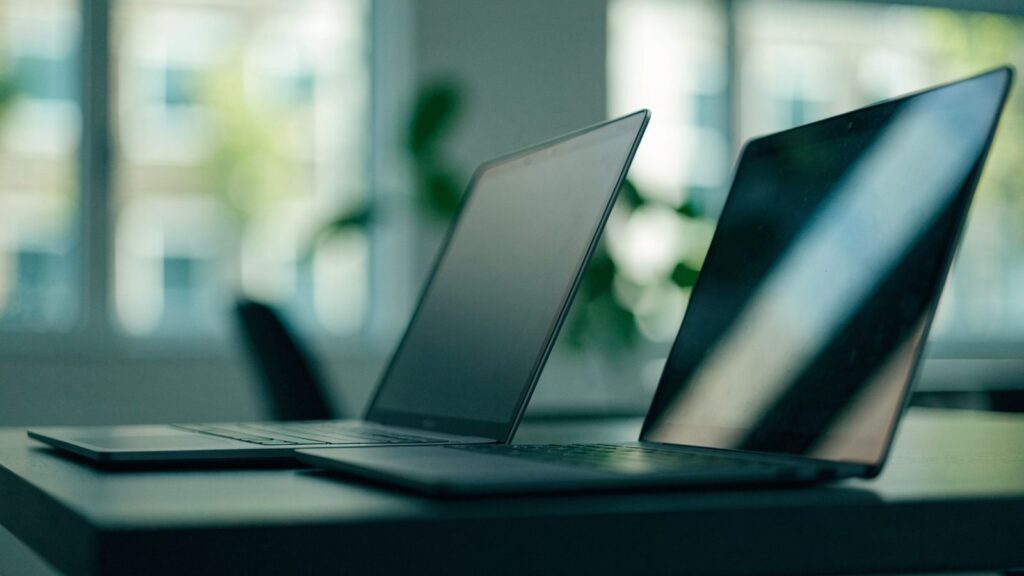 Two laptops side by side on an office desk as if being compared