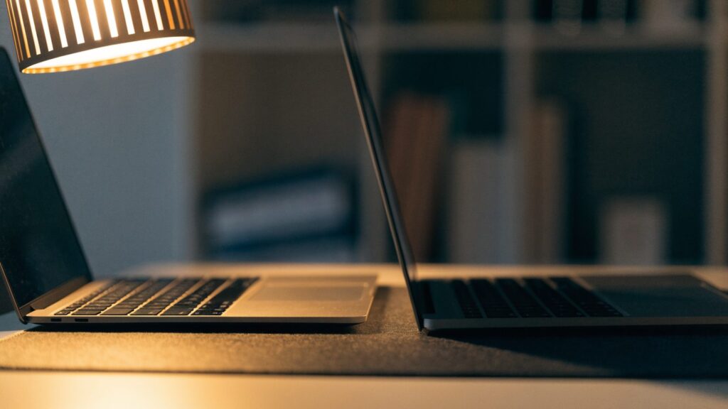 Two laptops side by side on a dark desk mat as if being compared