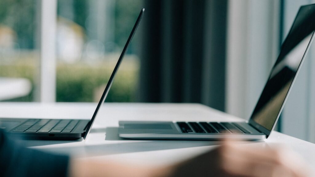 Two laptops side by side on a white desk as if being compared