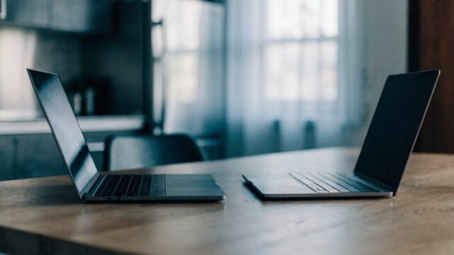 Two laptops side by side on a kitchen table as if being compared