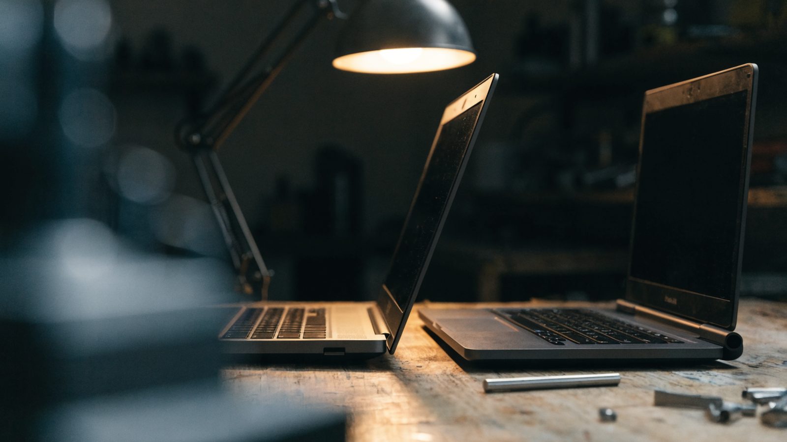 Two laptops side by side on a workbench as if being compared
