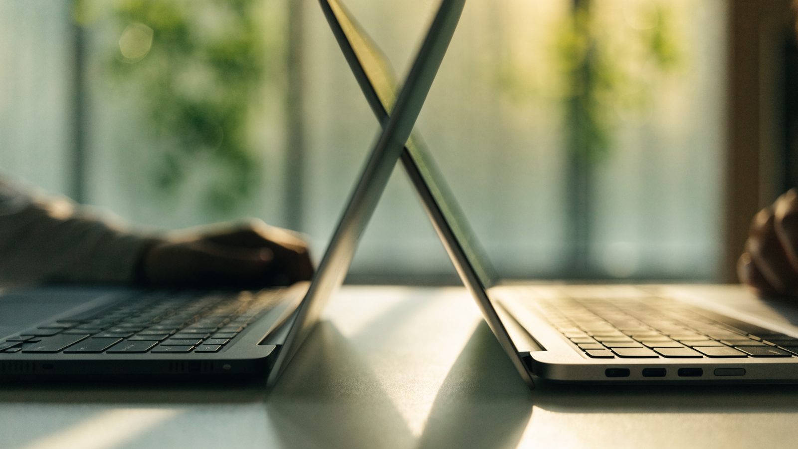 Two laptops side by side on a white desk as if being compared