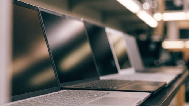 A row of new laptops on display on a store shelf