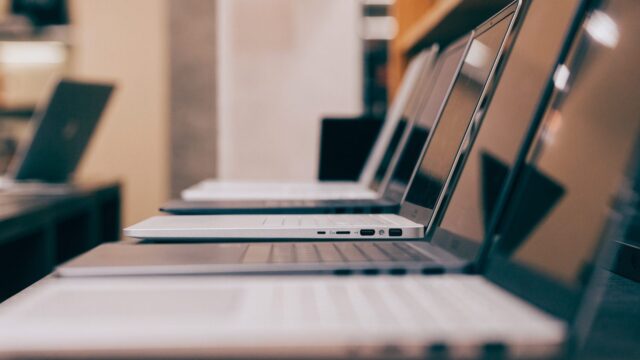 A row of new laptops on display on a store shelf