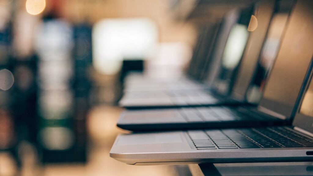 A row of new laptops on display on a store shelf