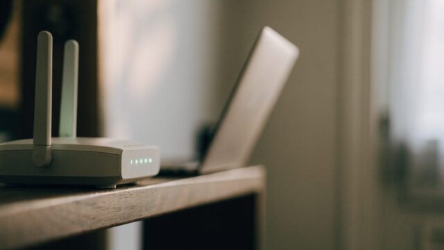 A home wifi router with softly glowing indicator lights on a shelf