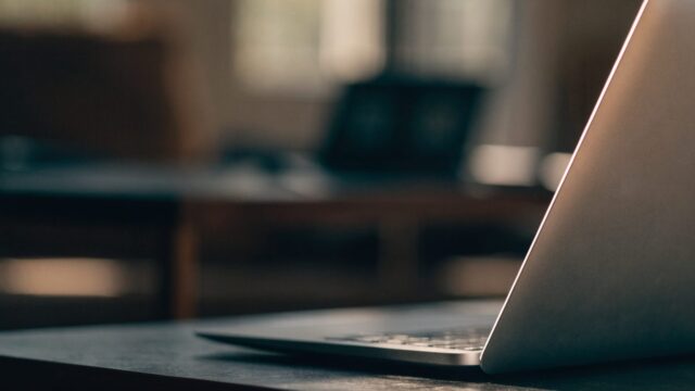 A slim matte grey laptop half open photographed from the side