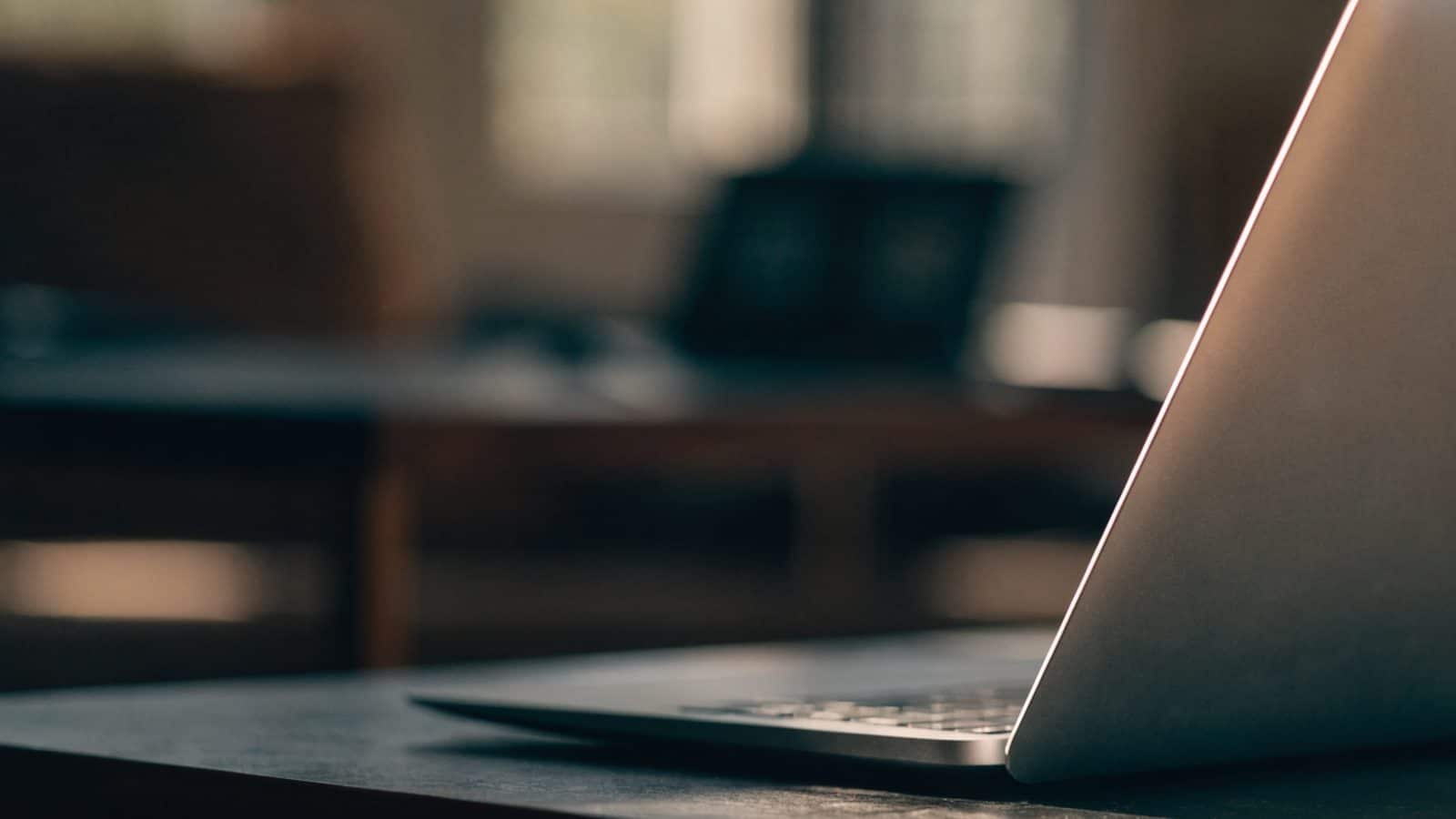 A slim matte grey laptop half open photographed from the side