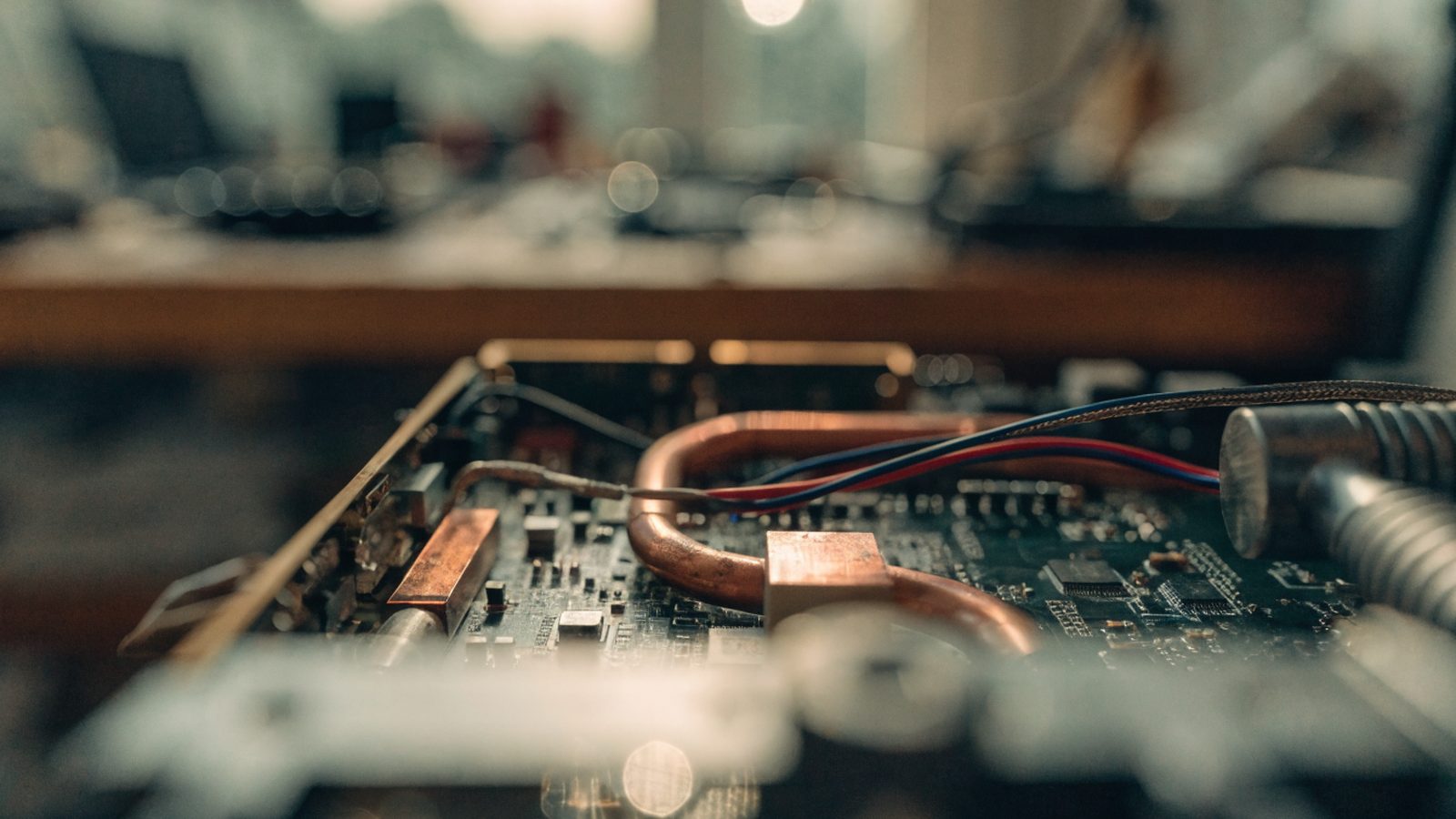 Close-up of a laptop motherboard with copper heat pipes during a repair