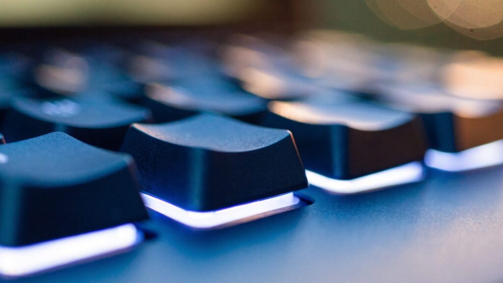 Macro close-up of backlit keys on a dark blue laptop keyboard