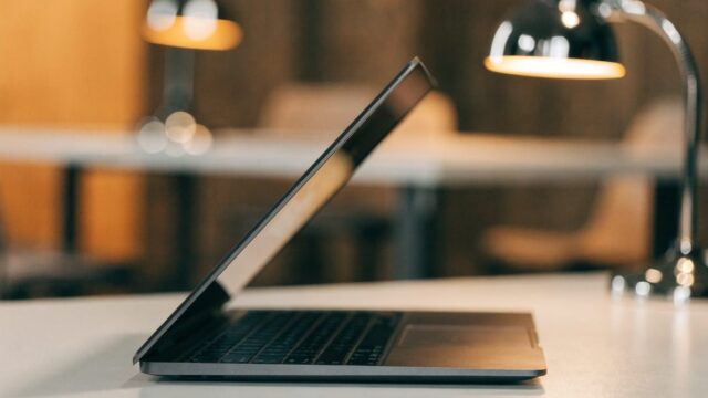 A half-closed graphite black laptop on a white desk