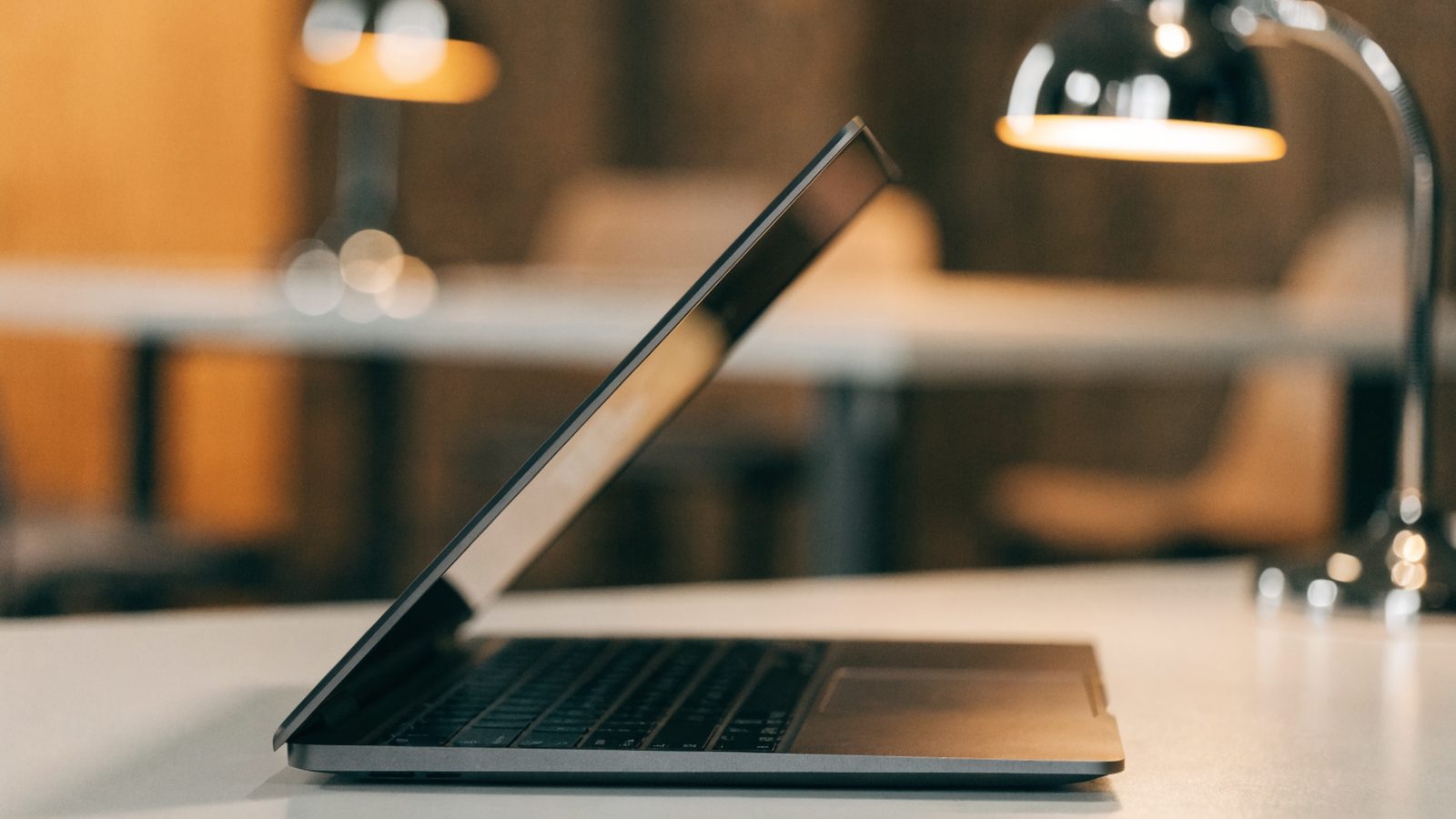 A half-closed graphite black laptop on a white desk