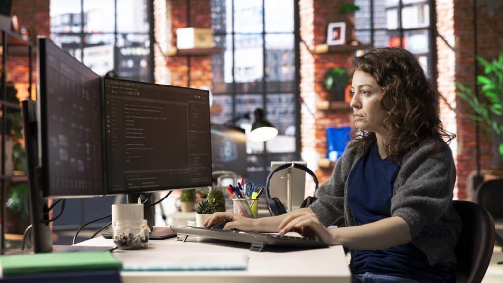 IT specialist at workstation programming on monitor and writing lines of code