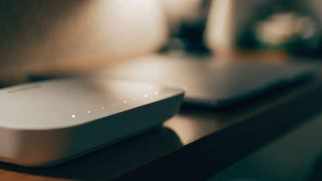 A home wifi router with softly glowing indicator lights on a shelf