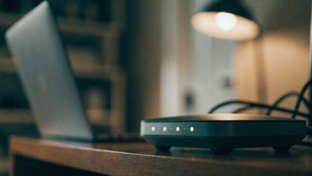 A home wifi router with softly glowing indicator lights on a shelf