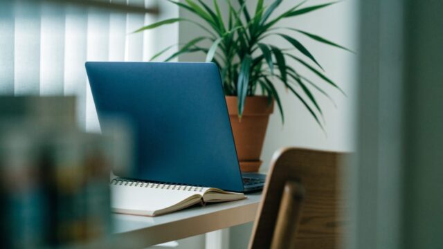 A tidy home office desk with a dark blue laptop
