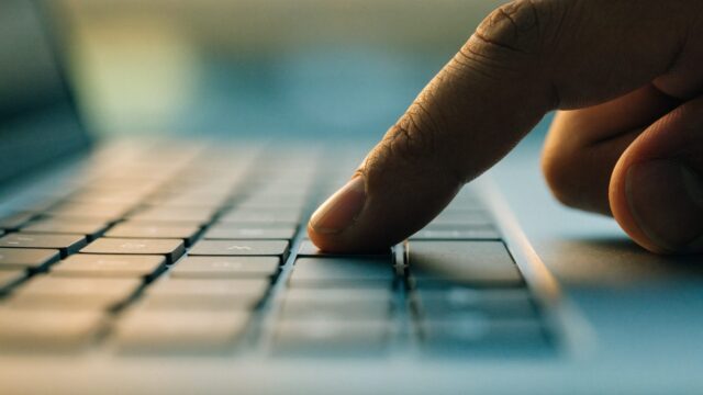 Close-up of a single key being pressed on a matte grey laptop keyboard