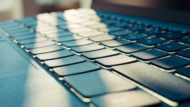 Macro close-up of backlit keys on a dark blue laptop keyboard