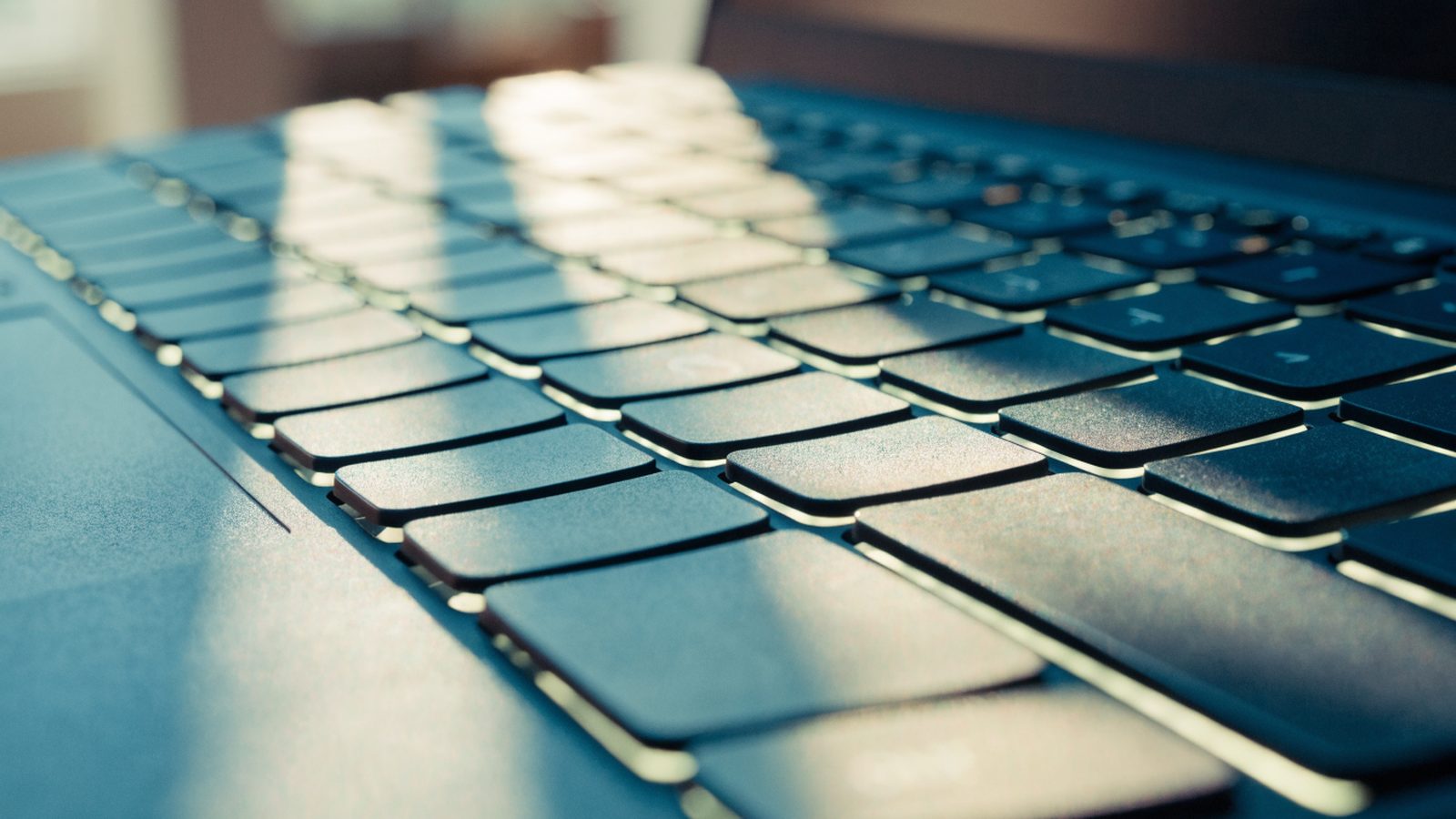 Macro close-up of backlit keys on a dark blue laptop keyboard