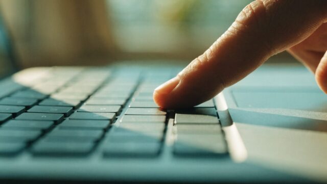 Close-up of a single key being pressed on a matte grey laptop keyboard