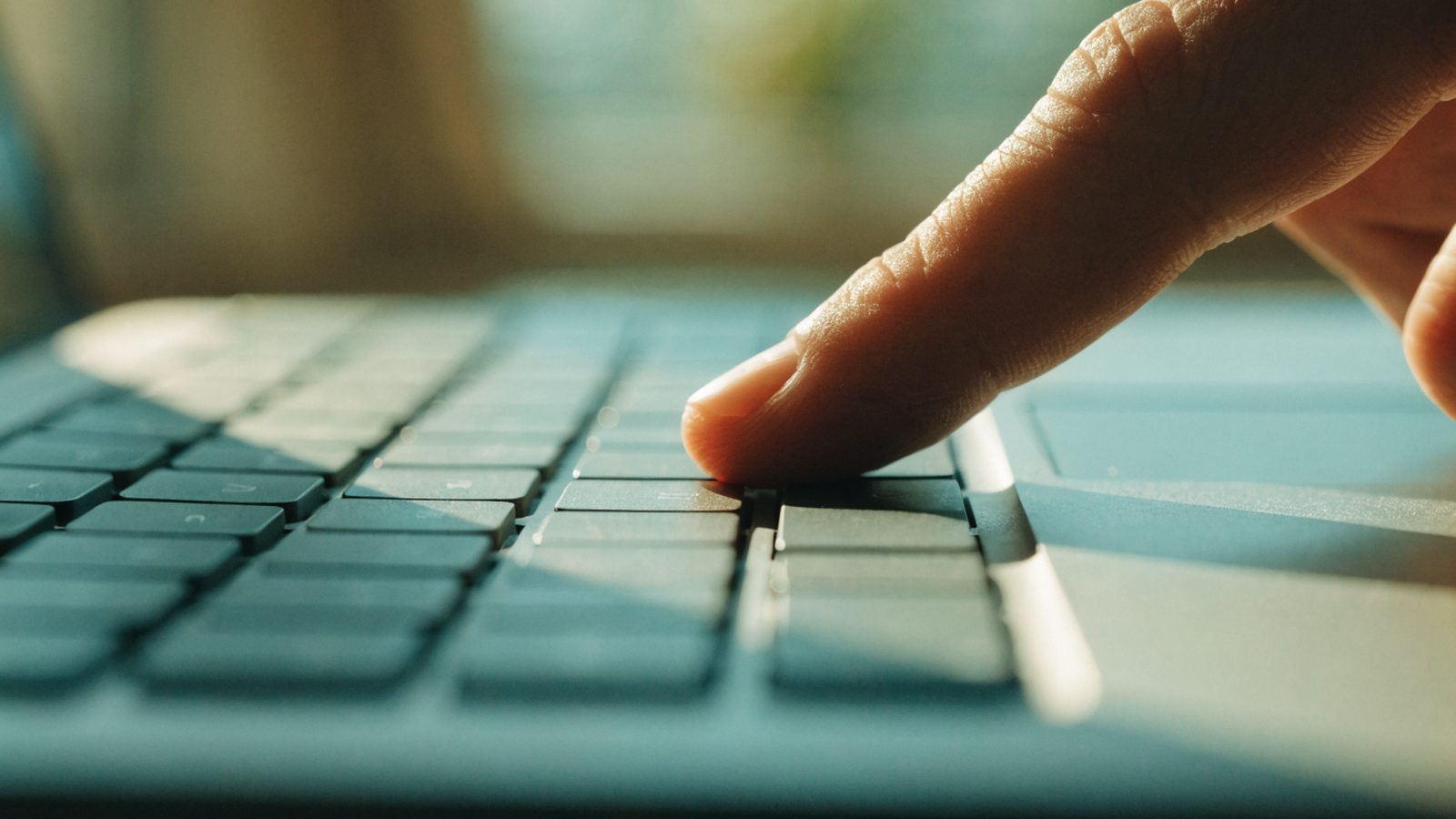 Close-up of a single key being pressed on a matte grey laptop keyboard