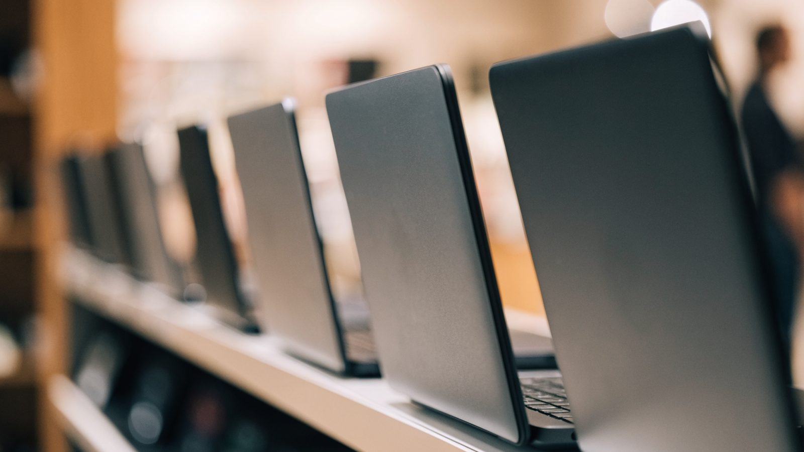 A row of new laptops on display on a store shelf