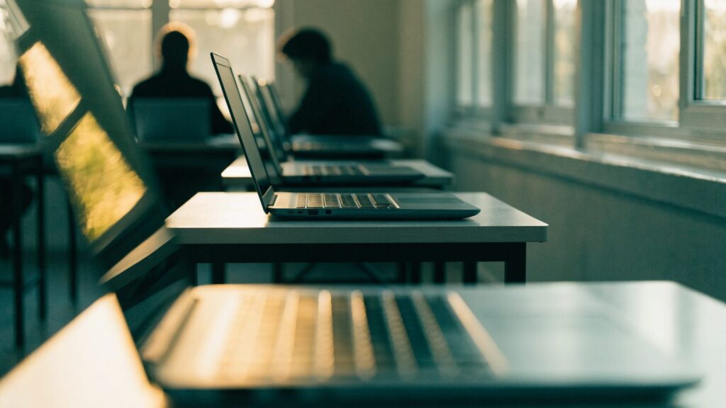 A row of laptops on desks in a school computer lab