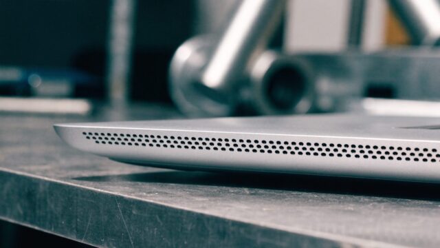 Close-up of the speaker grille edge of a silver laptop on a workbench