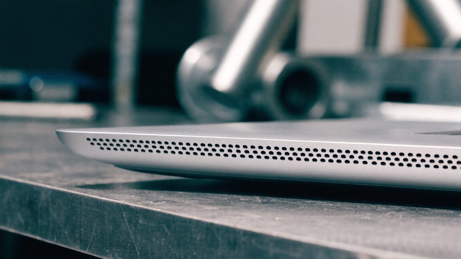 Close-up of the speaker grille edge of a silver laptop on a workbench
