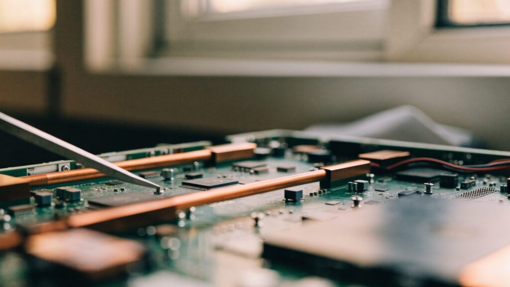 Close-up of a laptop motherboard with copper heat pipes during a repair