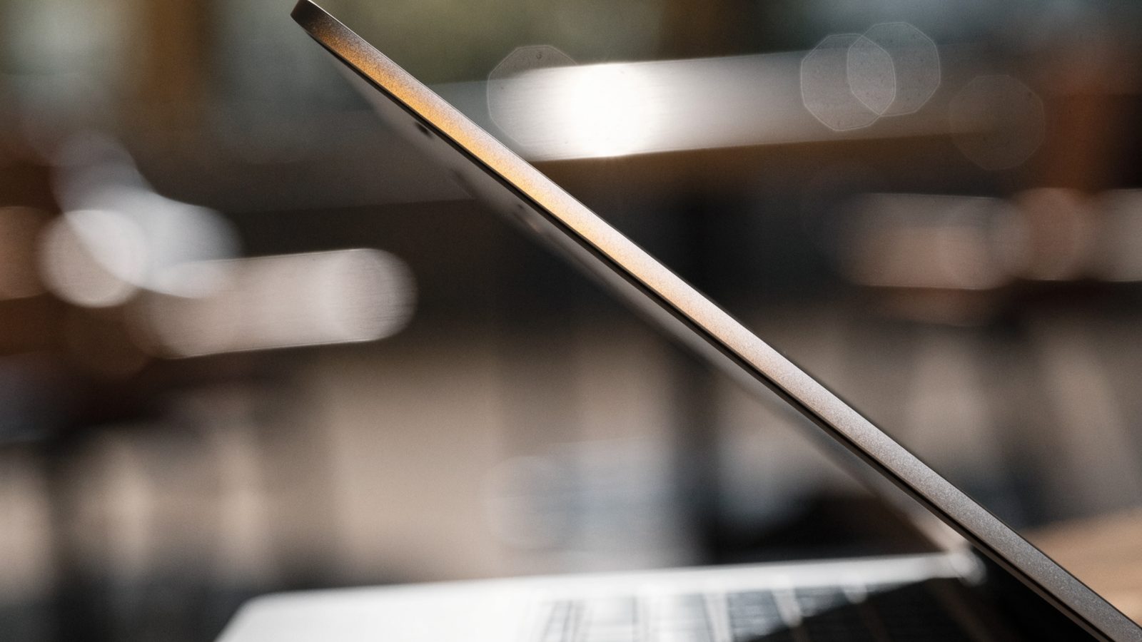A slim silver laptop half open photographed from the side