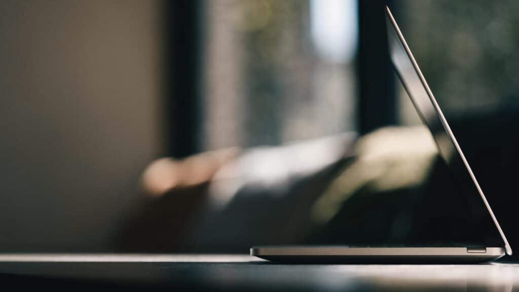 A slim silver laptop half open photographed from the side