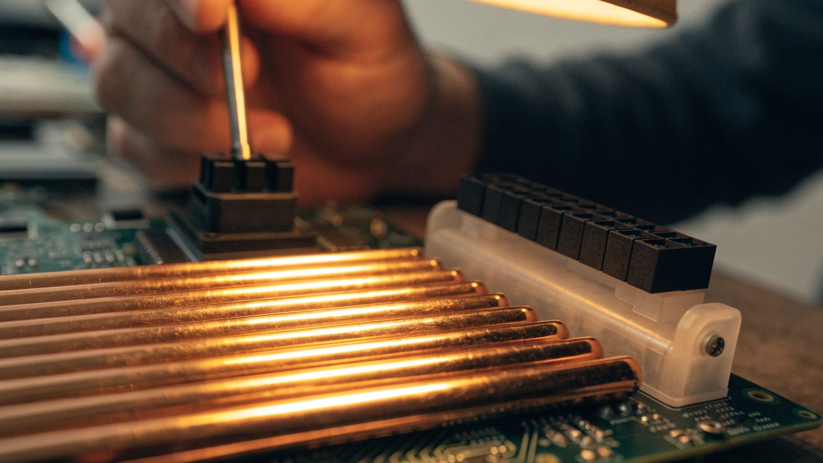 Close-up of a laptop motherboard with copper heat pipes during a repair