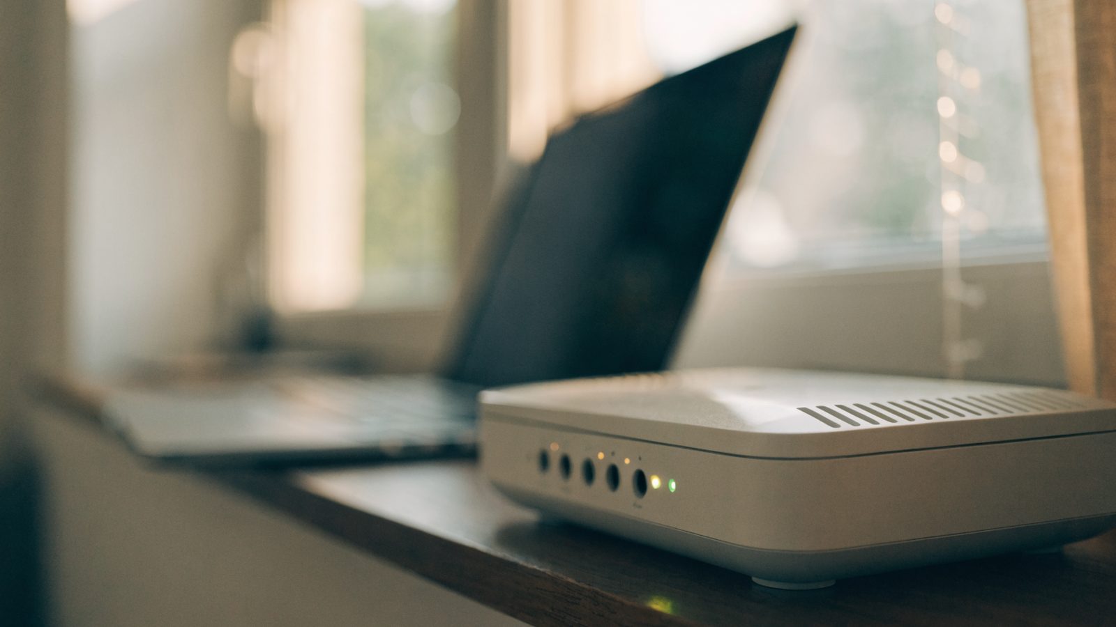 A home wifi router with softly glowing indicator lights on a shelf